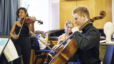 Strings chamber musicians in a practice room, preparing for a performance